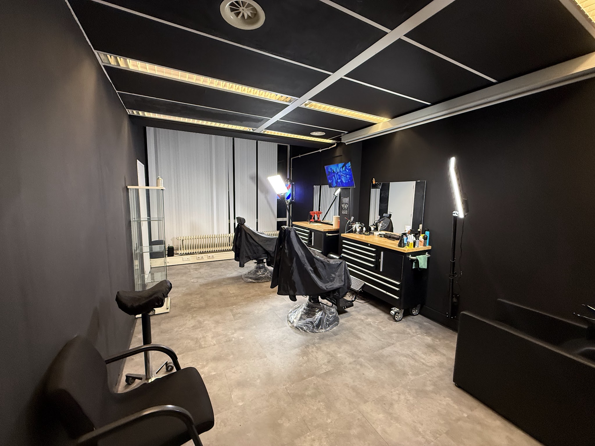 De studio van binnen: zwarte wanden, twee kappersstoelen en strakke verlichting
