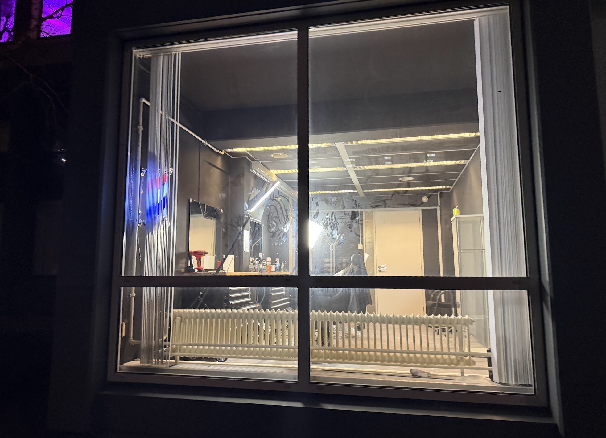 De studio in de avond, gezien door het raam, met de verlichting aan
